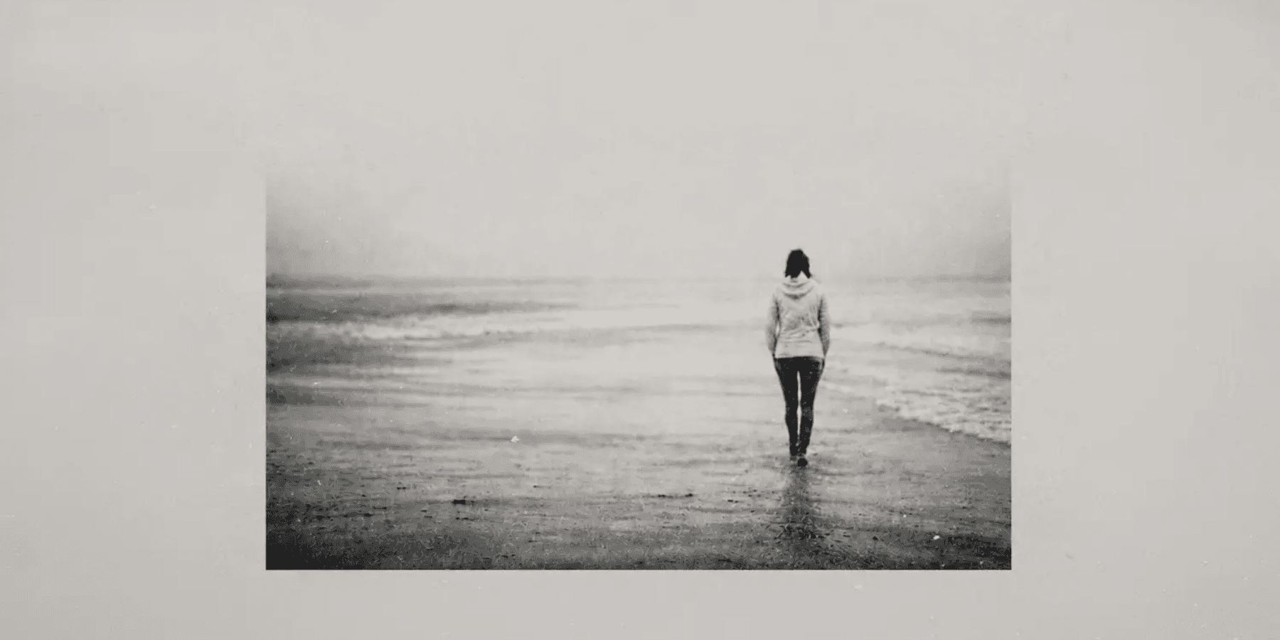 Entimental Tourists solitary figure walking on vast empty beach landscape