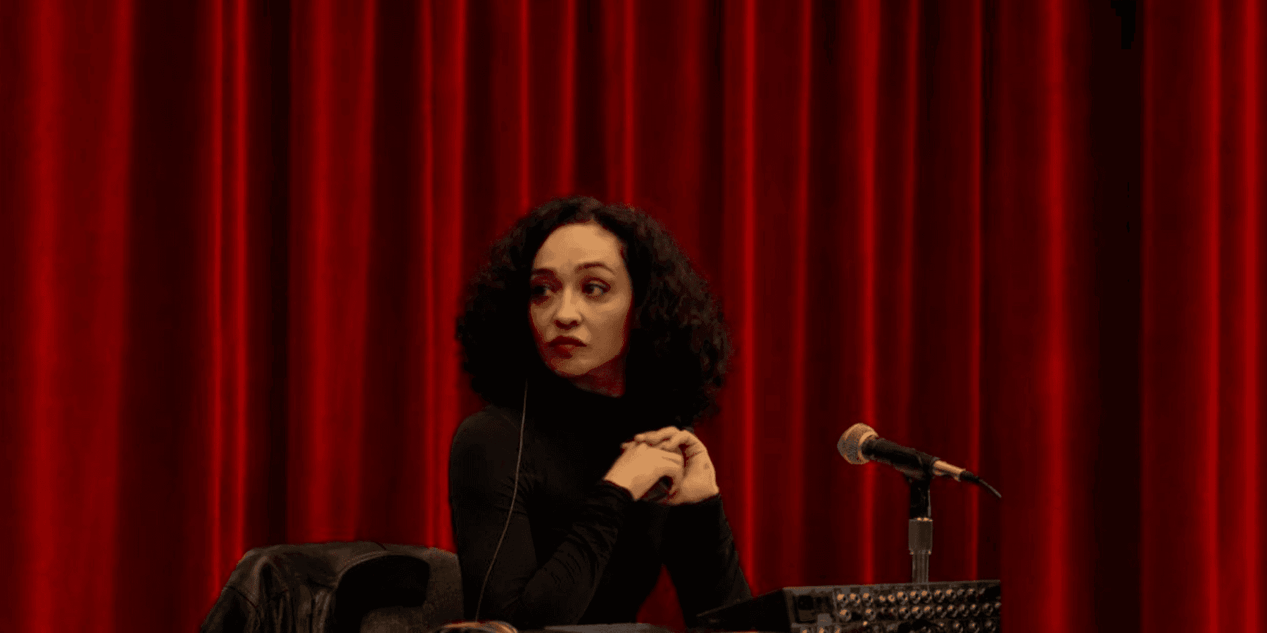 Radio Bette female singer performing at microphone in front of red velvet curtain